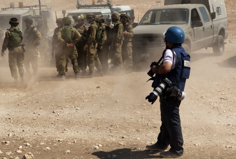 A photographer in a conflict setting with soldiers 