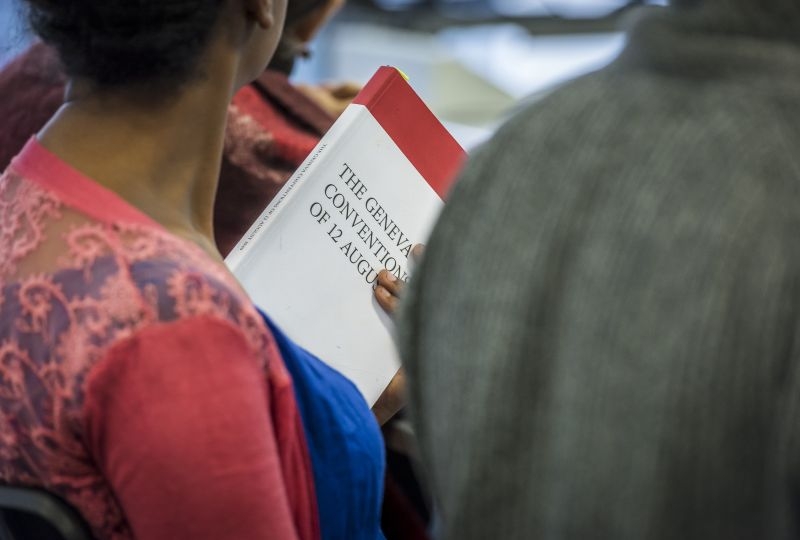 A person holding the Geneva Conventions book