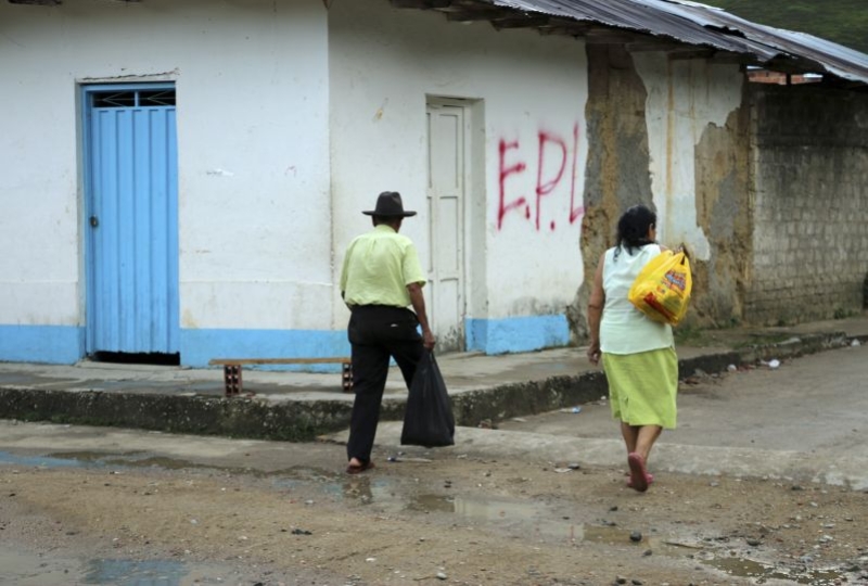 Colombia,  Norte de Santander deparment, Las Mercedes. Couple walk by a graffiti of an armed group